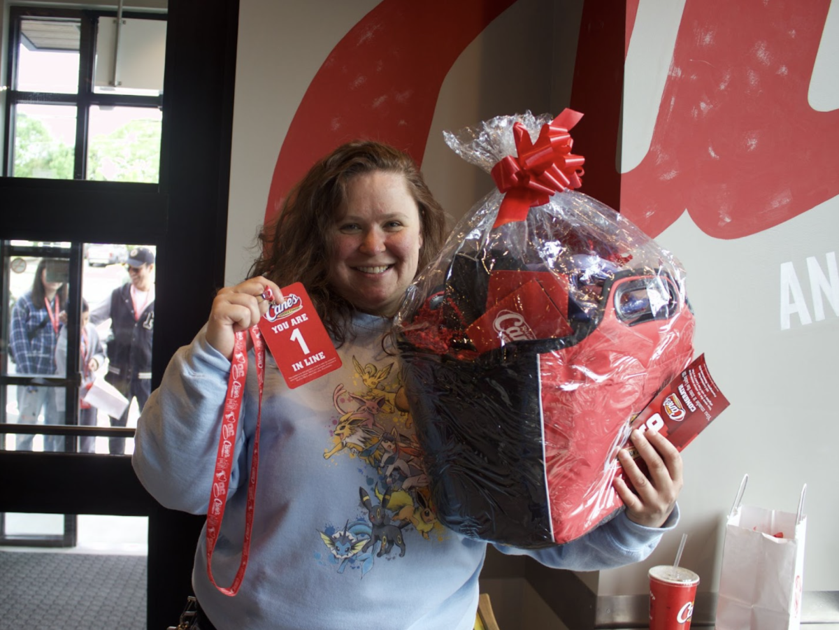 The first customer at Raising Cane’s Southboro resident Michelle Hebee poses for a photo holding her #1 customer badge and lanyard, along with a basket of gifts and goodies from Cane’s.